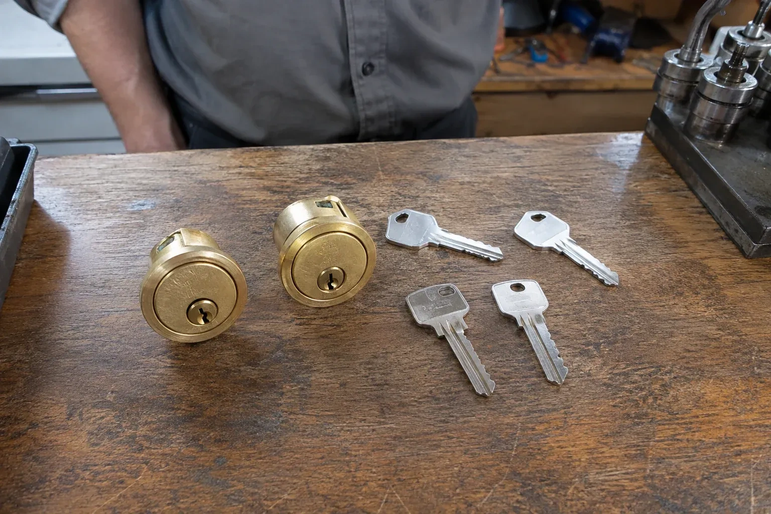Two detached brass lock cylinders and four house keys on a wooden counter. — Lock Rekeying, Richmond Hill
